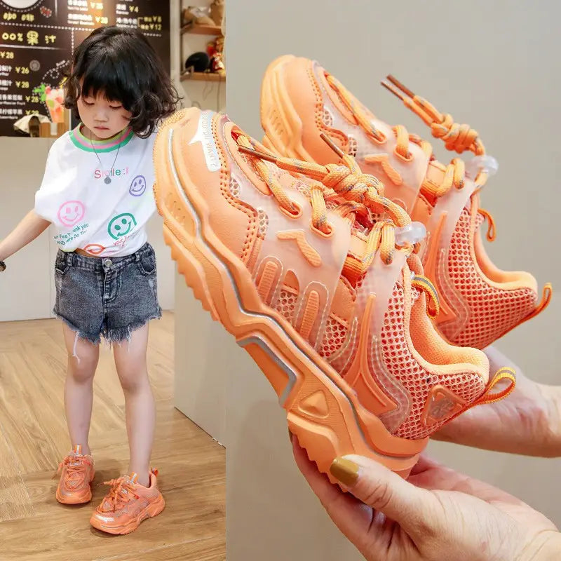orange translucent mesh sneakers with chunky soles and matching laces designed as older children’s casual sports shoes.