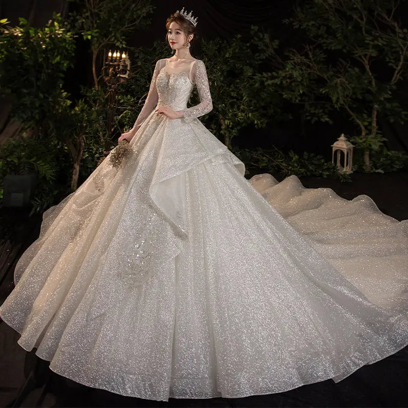 A sparkling white wedding evening dress with long sleeves and a voluminous skirt adorned with intricate beading and sequins in the french temperament dream collection.