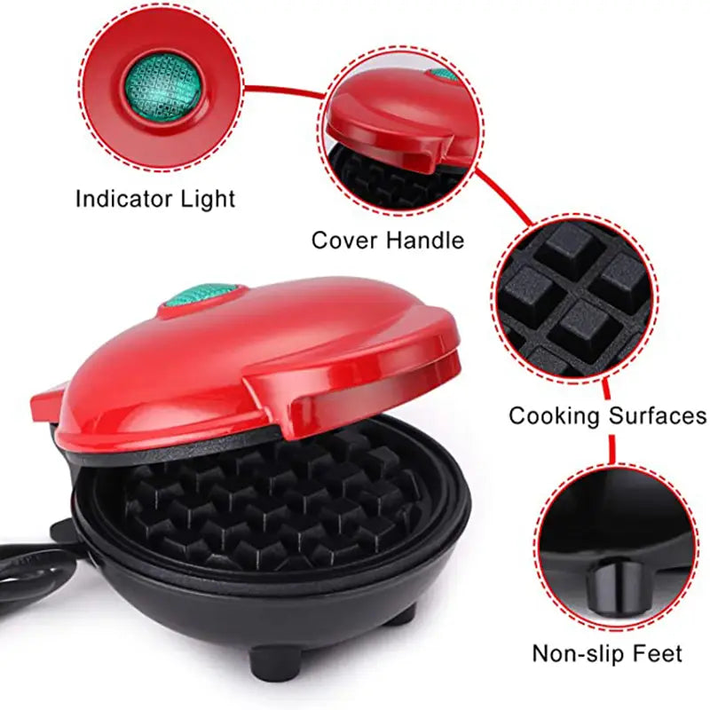 Mini electric waffle maker in red and black with a green indicator light, cover handle, grid-patterned cooking surfaces, and non-slip feet.