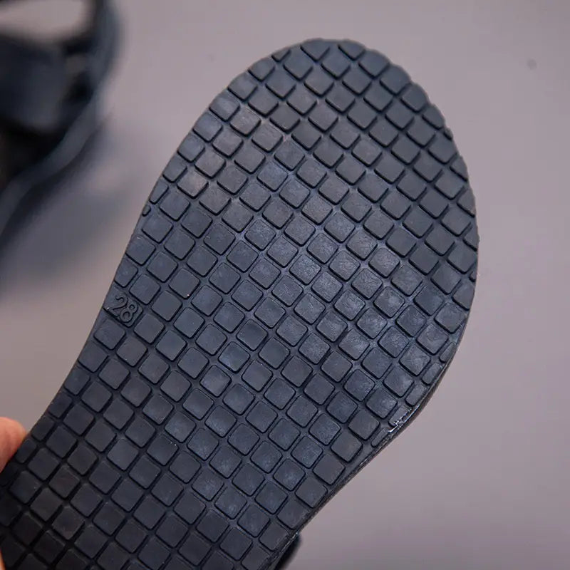 Black rubber sole with a grid pattern and size 28 imprint on childrens peach breathable casual shoes designed as school breathable casual footwear.