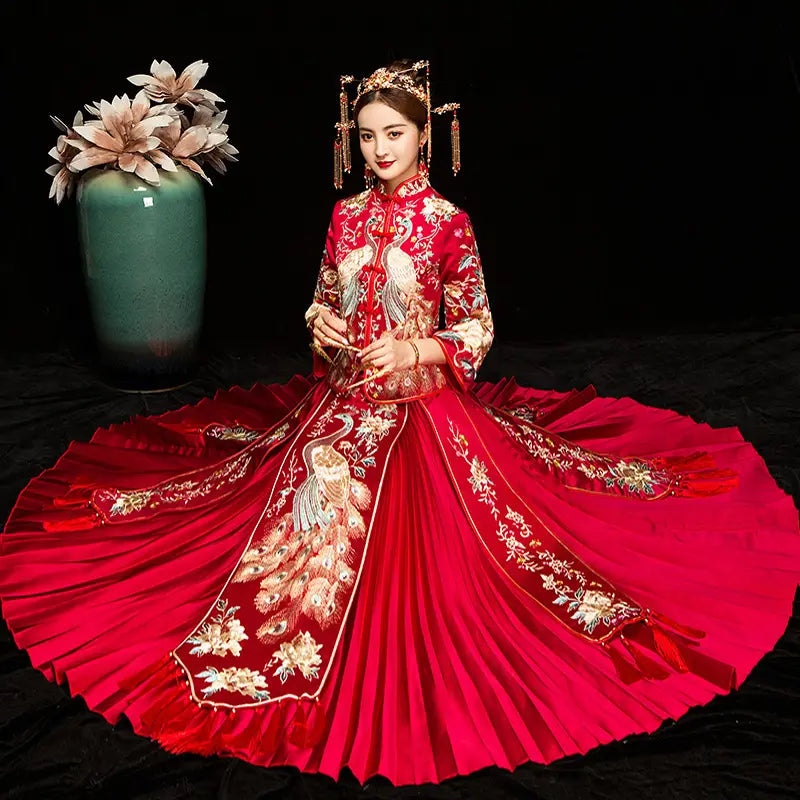 A vibrant red satin wedding gown featuring intricate gold and white peacock embroidery with a high collar and flowing pleated skirt from the embroidered kimono chinese wedding suits collection.