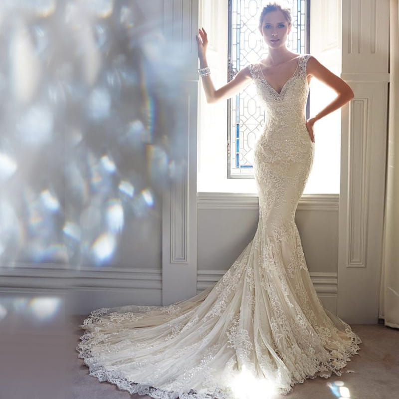 a cream-colored mermaid-style wedding gown with intricate lace detailing and a v-neckline designed for sexy halter brigade shooting seaside events