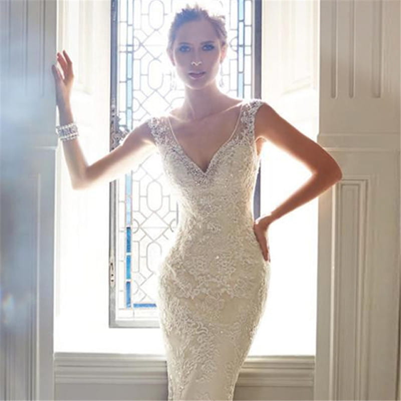 A cream-colored, form-fitting sexy halter brigade wedding gown with shimmering mermaid silhouette, intricate lace detailing, and a v-neckline.