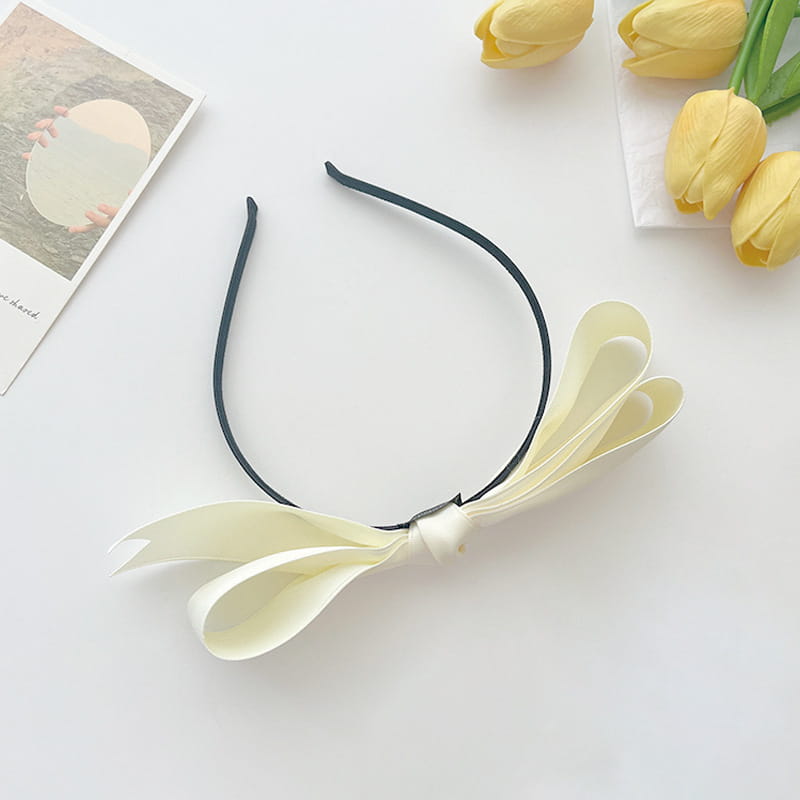 A delicate black satin bow headband for women featuring a large cream-colored french satin bow.