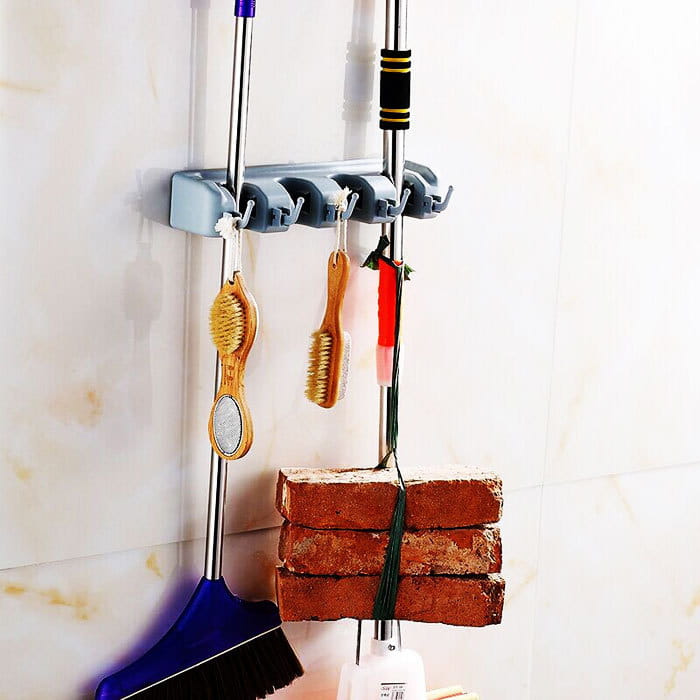 Gray plastic mop hook wall-mounted organizer rack with four hooks for hanging brooms and mops on a hook wall hanging system.
