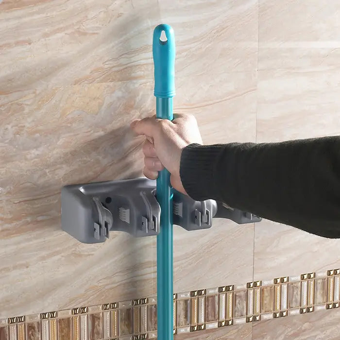 blue plastic mop handle held by a gray plastic plastic mop hook wall mounted for mop hook wall hanging organizer rack