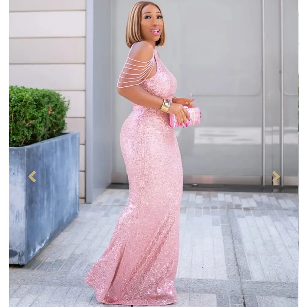A shimmering pink sequined african ladies quality high stretch dress with off-the-shoulder straps and a fitted silhouette.