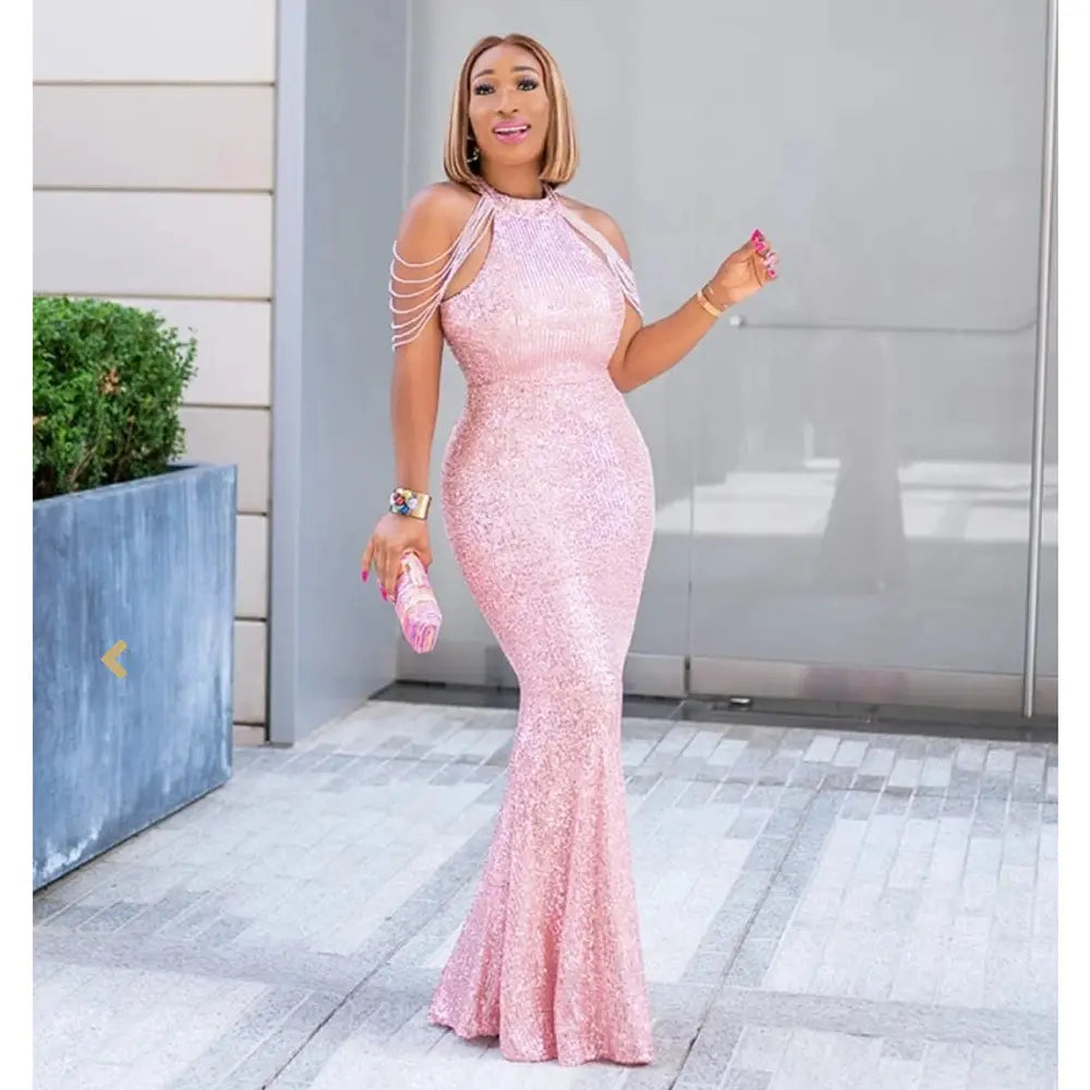 A shimmering pink lace mermaid gown with a halter neckline and delicate shoulder straps showcasing african ladies quality high stretch material.