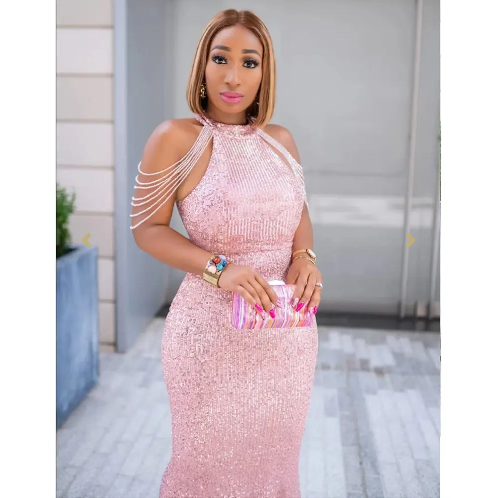 A shimmering pink sequined african ladies quality high stretch gown with halter neckline and off-the-shoulder detailing.