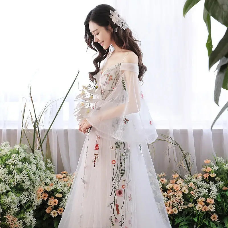 Off-the-shoulder retro bridal gown in gray tulle featuring delicate sheer sleeves and intricate soft pink and red floral embroidery ideal as a wedding dress.