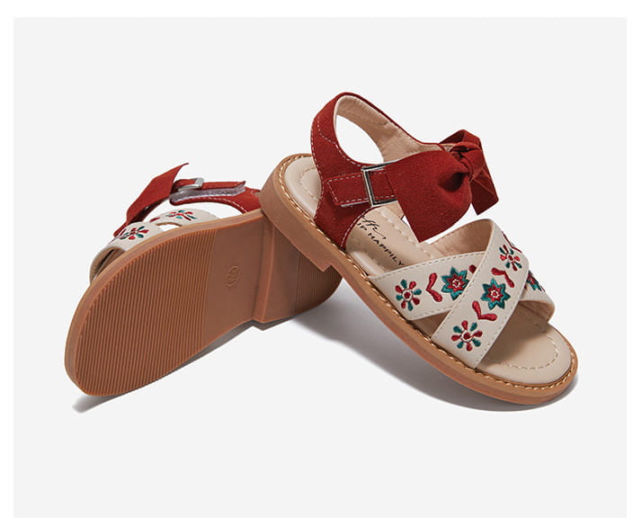 Red and cream embroidered big children’s soft-soled sandals with a floral design and bow detail on the strap.