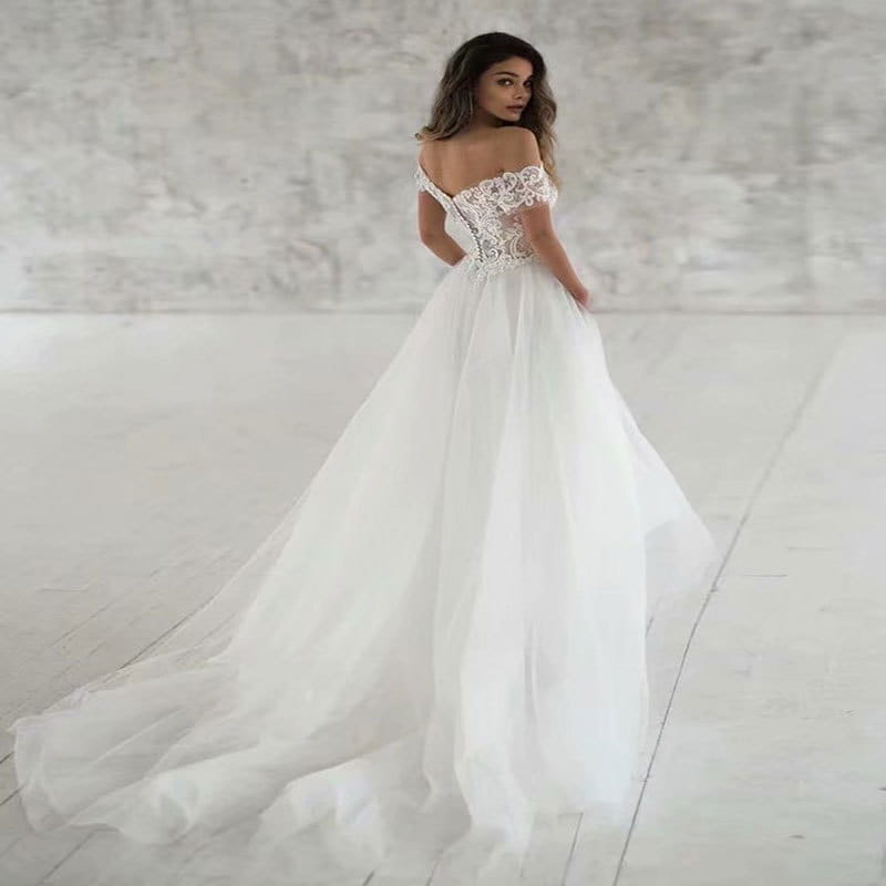 A flowing white off-the-shoulder wedding dress featuring intricate lace detailing and a voluminous tulle skirt, perfect as an elegant lace light wedding dress.