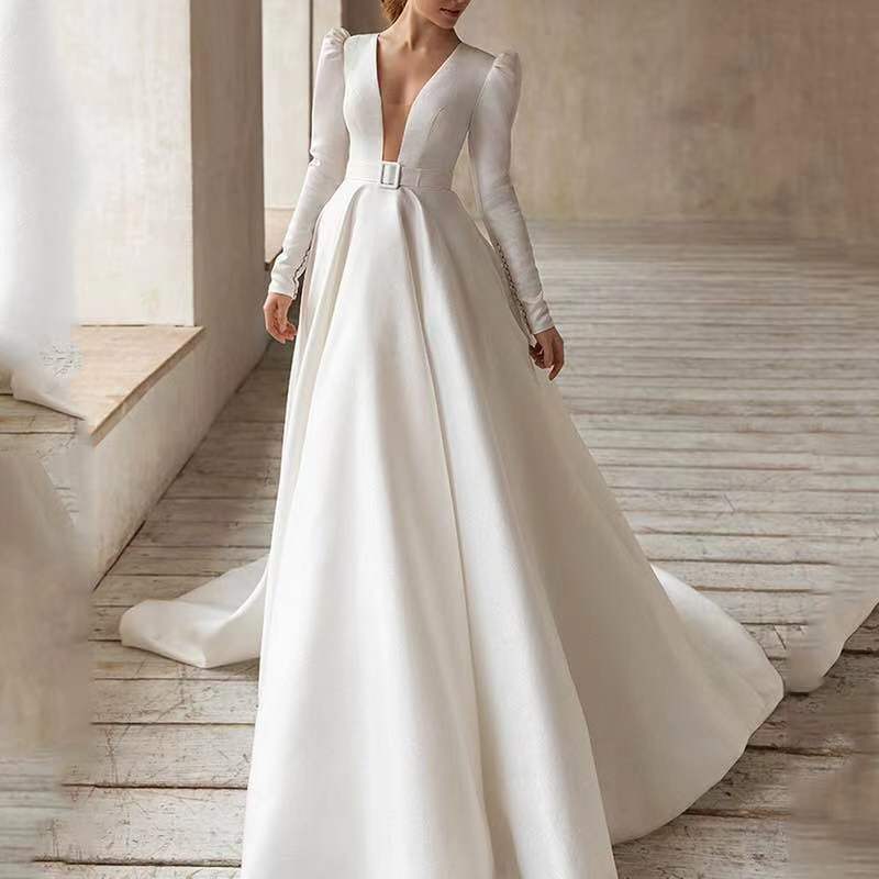 A sleek white satin wedding dress with long sleeves, a deep v-neckline, an elegant fitted waist with a silver buckle, and a flowing long skirt made of polyester fiber.