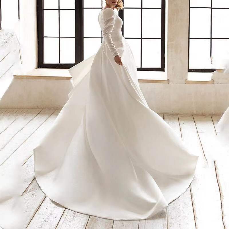 A flowing white satin wedding dress with long sleeves high neckline and dress long skirt made of polyester fiber.