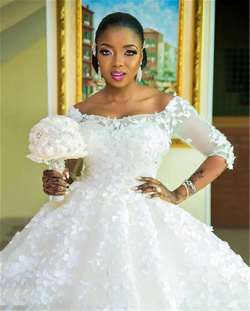 A white off-the-shoulder wedding dress for pregnant women princess featuring intricate floral appliqués and lace three-quarter length sleeves.