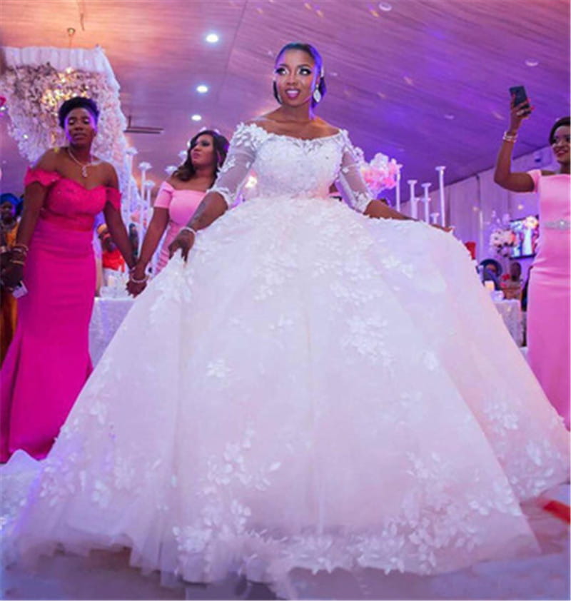 A white off-the-shoulder pregnant women princess wedding dress with intricate floral lace appliqués and sheer long lace sleeves.