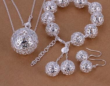 Silver spherical ball pendant jewelry featuring intricate filigree design and a small black symbol engraved on the surface from exquisite jewelry.