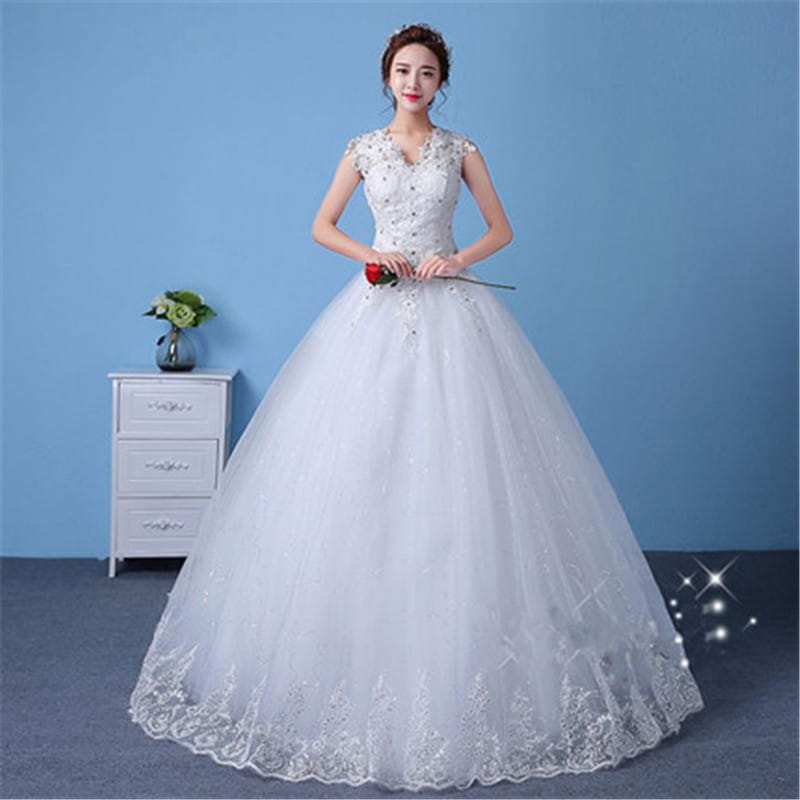 A white floor-length wedding dress with intricate lace detailing and beaded embellishments on the bodice and skirt hem designed for a wedding.
