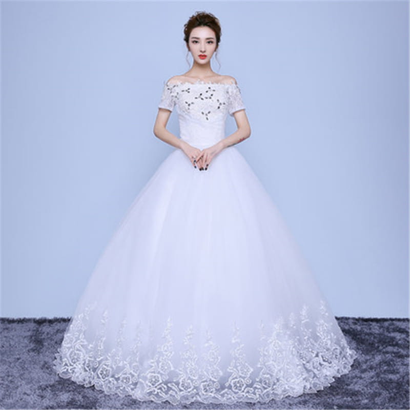 A white off-the-shoulder wedding dress with short sleeves, intricate lace and beaded detailing on the bodice and hemline, and a voluminous tulle skirt suitable for a floor-length wedding gown.