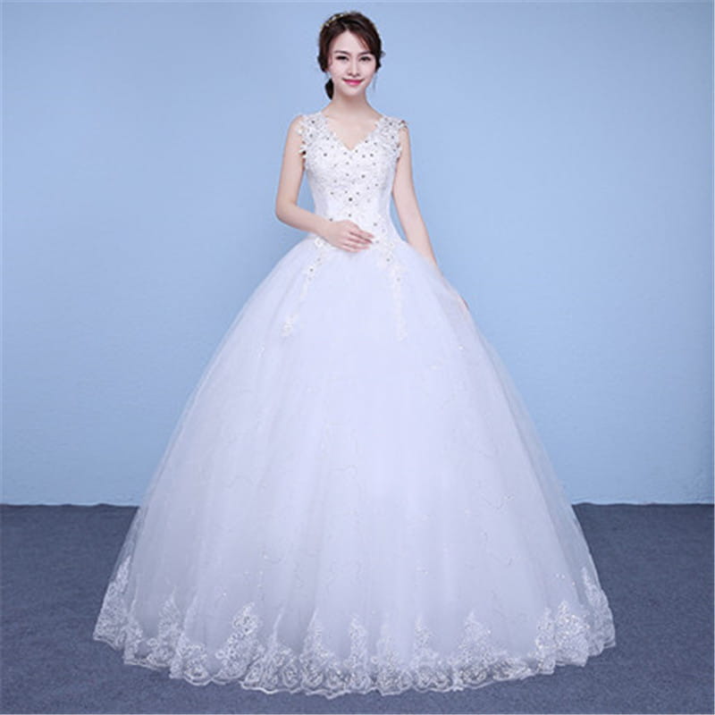 A white sleeveless floor length wedding dress with a v-neckline adorned with sparkling embellishments and delicate lace trim along the hem.
