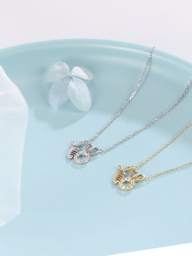 Two delicate 18k gold plated rabbit pendant necklaces in silver and gold featuring dangling carrot charms with sparkling stones.