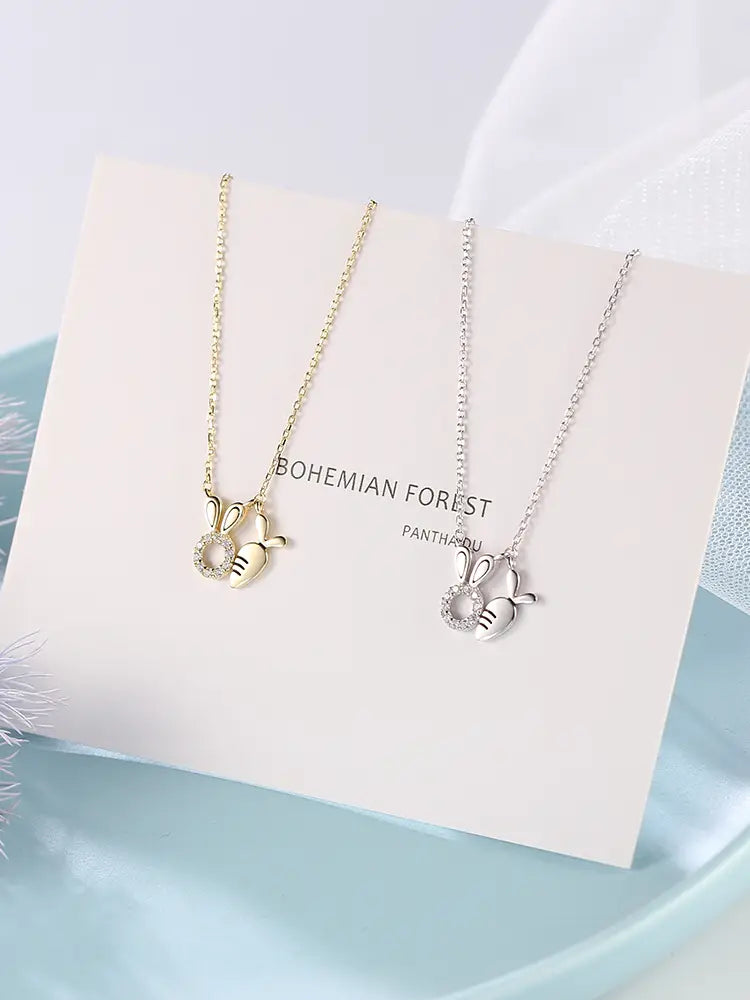 Two delicate 18k gold plated rabbit pendant necklaces in gold and silver featuring small crystal-embedded carrot charms.