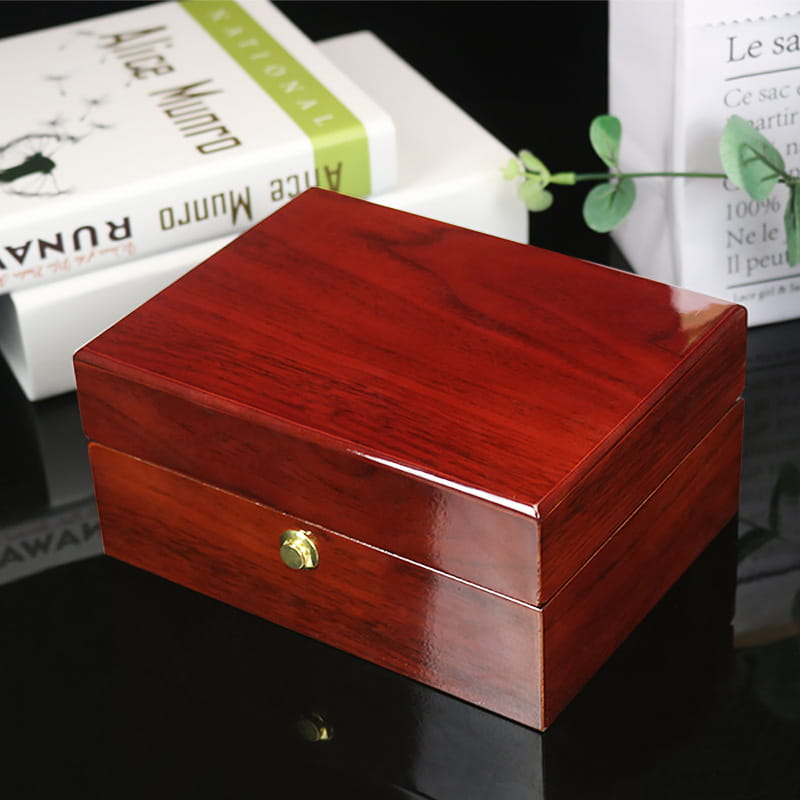 Polished reddish brown wooden watch box custom with a gold toned circular knob for secure storage of jewelry and timepieces.