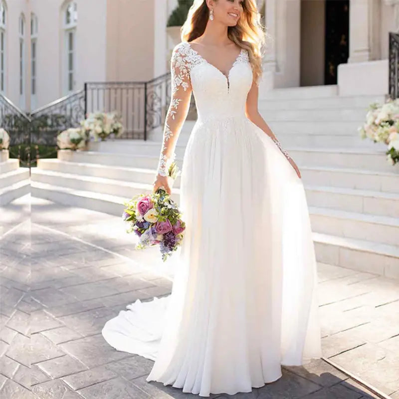 A flowing white lace wedding dress with long sleeves, delicate lace detailing, and a sexy backless deep v-neckline perfect for an evening dress.