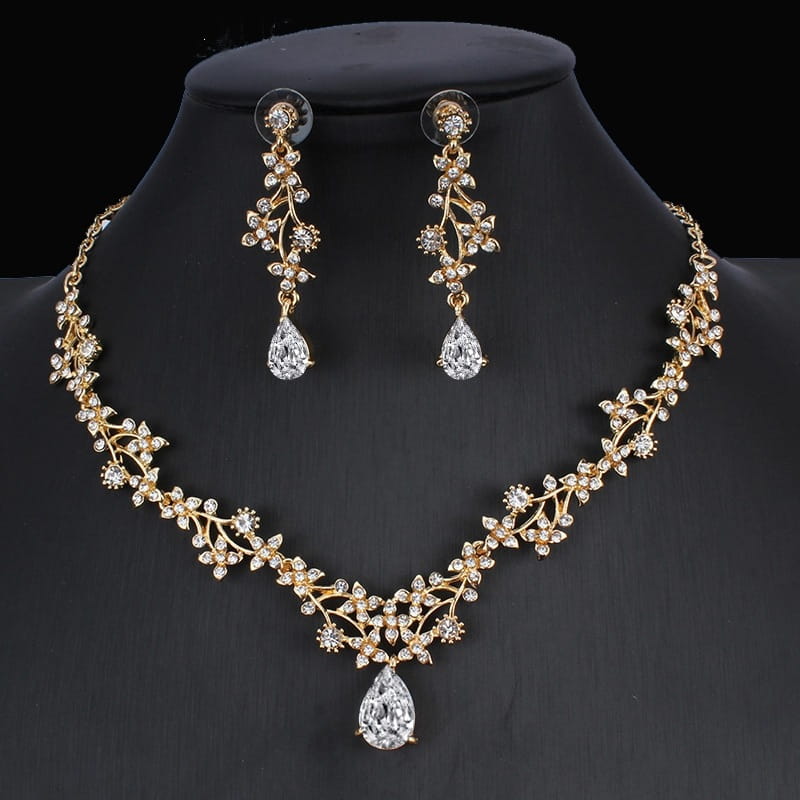 golden zircon jewelry set featuring gold-toned bridal necklace and matching drop earrings with intricate leaf and vine designs adorned with sparkling clear crystals and a central teardrop pendant.