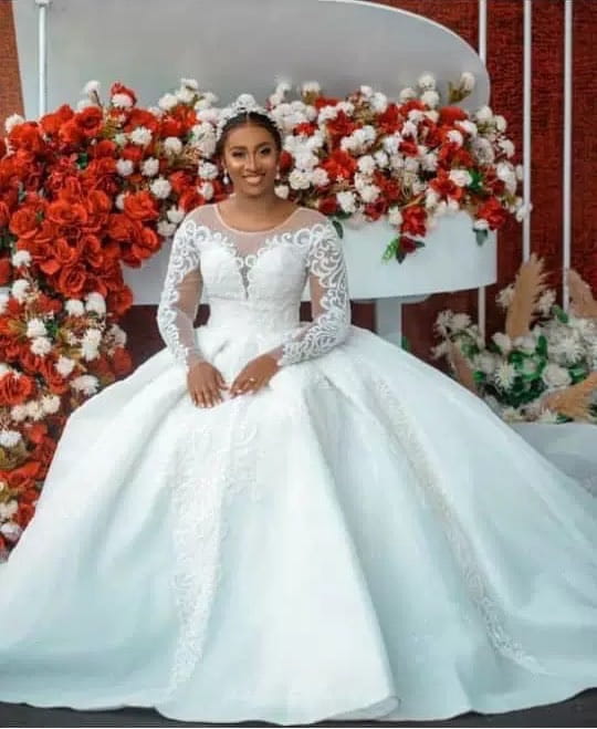 A white lace ball gown wedding dress with long sheer lace sleeves and a voluminous skirt designed as a wedding dress long for formal occasions.