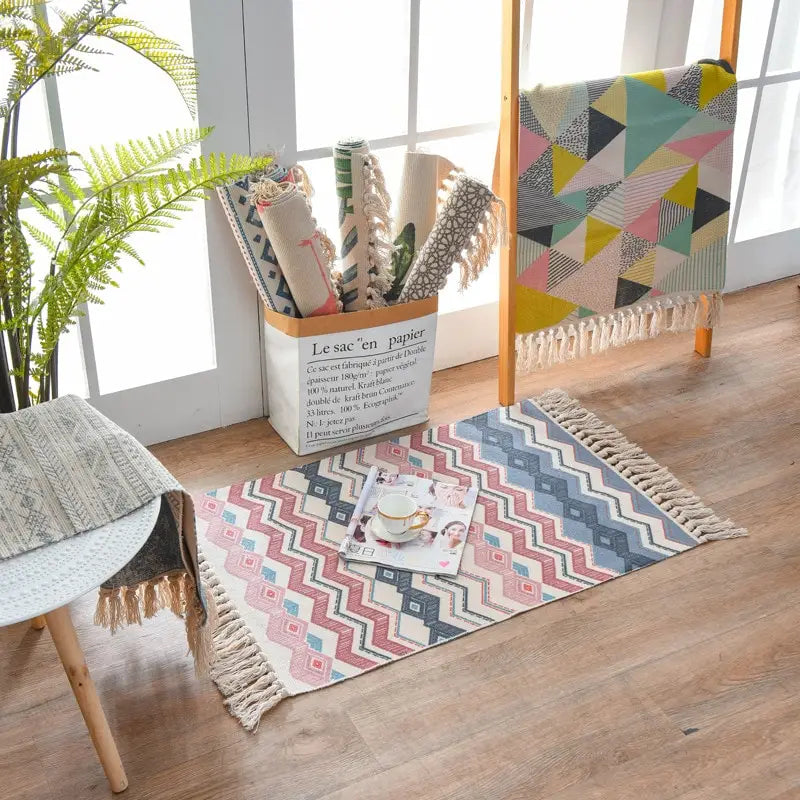 a rectangular scandinavian style linen cotton rug with a geometric zigzag pattern in shades of pink blue and beige featuring fringed tassel edges