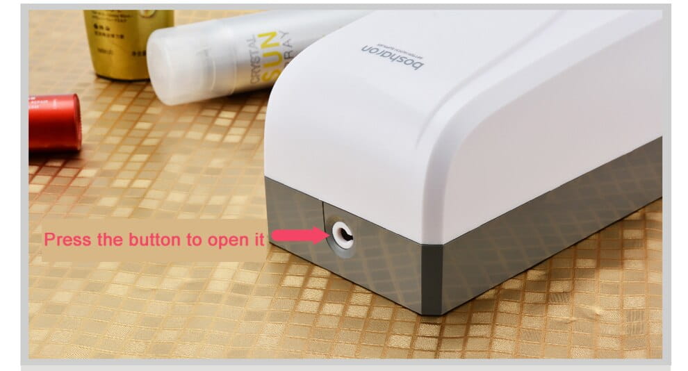 Modern wall mounted foam soap dispenser made of white and gray plastic with a rounded top and a small circular button for dispensing foam soap.