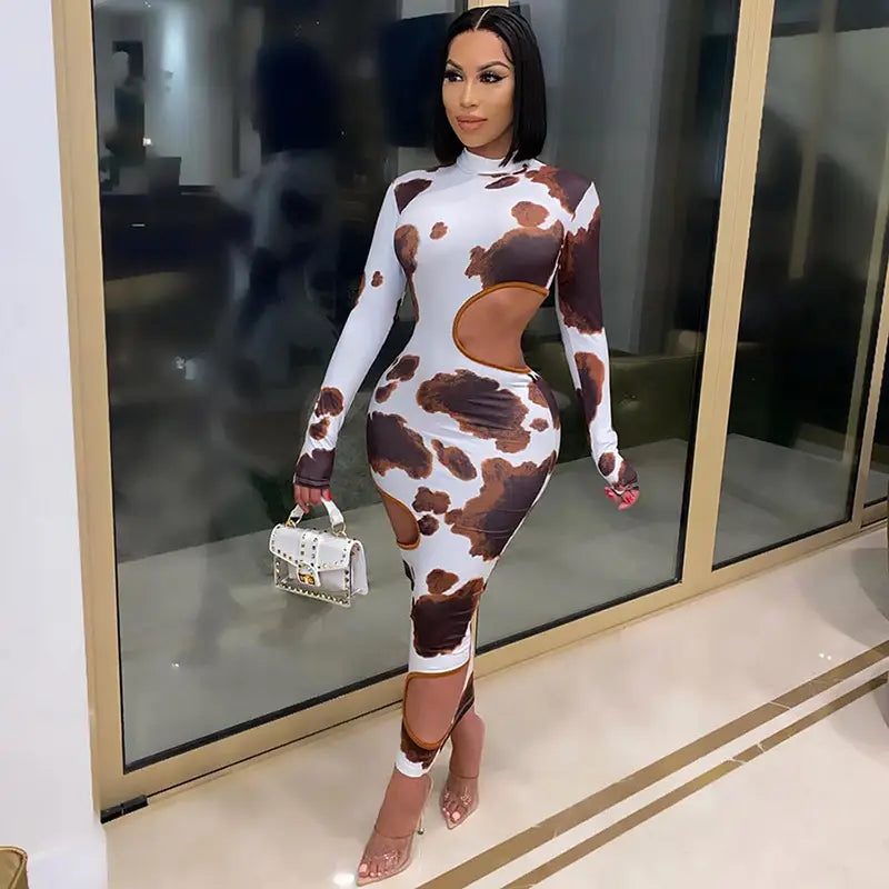 A form-fitting, long-sleeved cow print women irregular hole maxi dress in brown and white with weird puss hollow cut-out details.