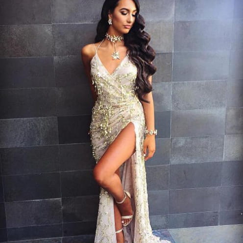 A shimmering silver beaded strap sequin dress featuring a sexy halter strap with a plunging v-neckline and high slit for evening wear.