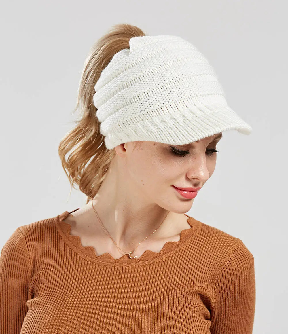 White knitted women ponytail beanie with a textured pattern and small brim suitable for autumn and winter use.