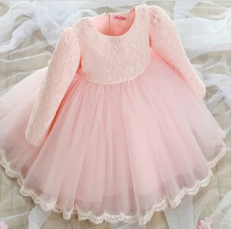 A delicate pink lace princess dress for girls featuring long lace sleeves and a layered tulle skirt with intricate white lace trim along the neckline armholes and hem suitable as a dress girls summer outfit.
