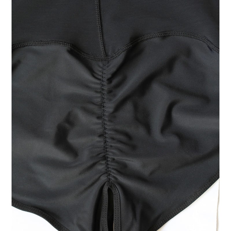 black stretchy plus size shaping underwear featuring a central ruched seam and matching stitching with a front zipper closure