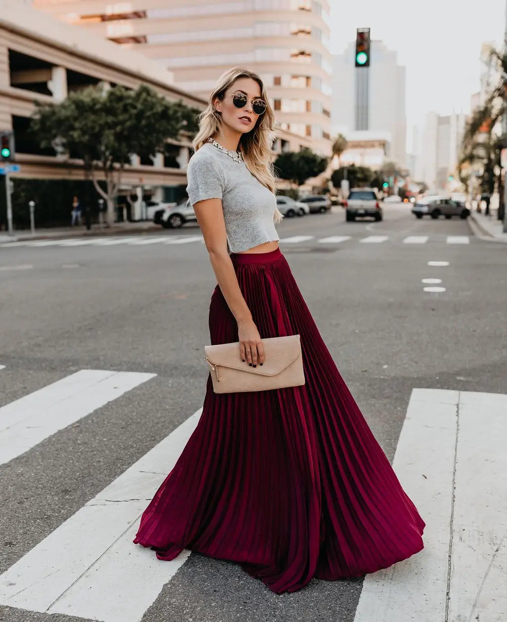 beige envelope clutch with a gold-tone zipper paired with red pleated high waist women fashion casual skirt highlighting skirt length and fashion casual style