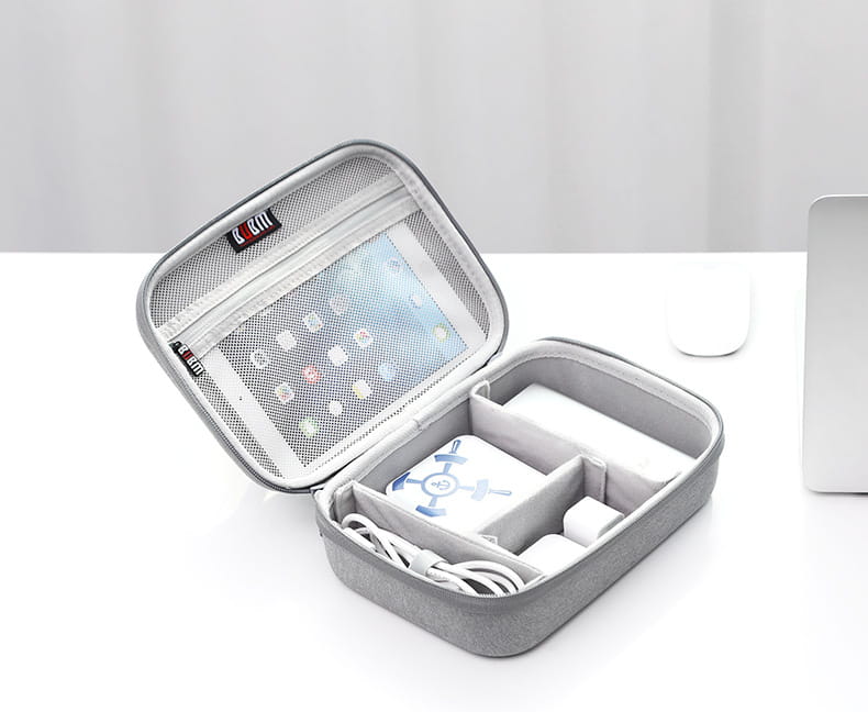 Gray textured fabric digital storage bag with mesh lining and internal compartments holding a tablet charger and cables for organized travel use.