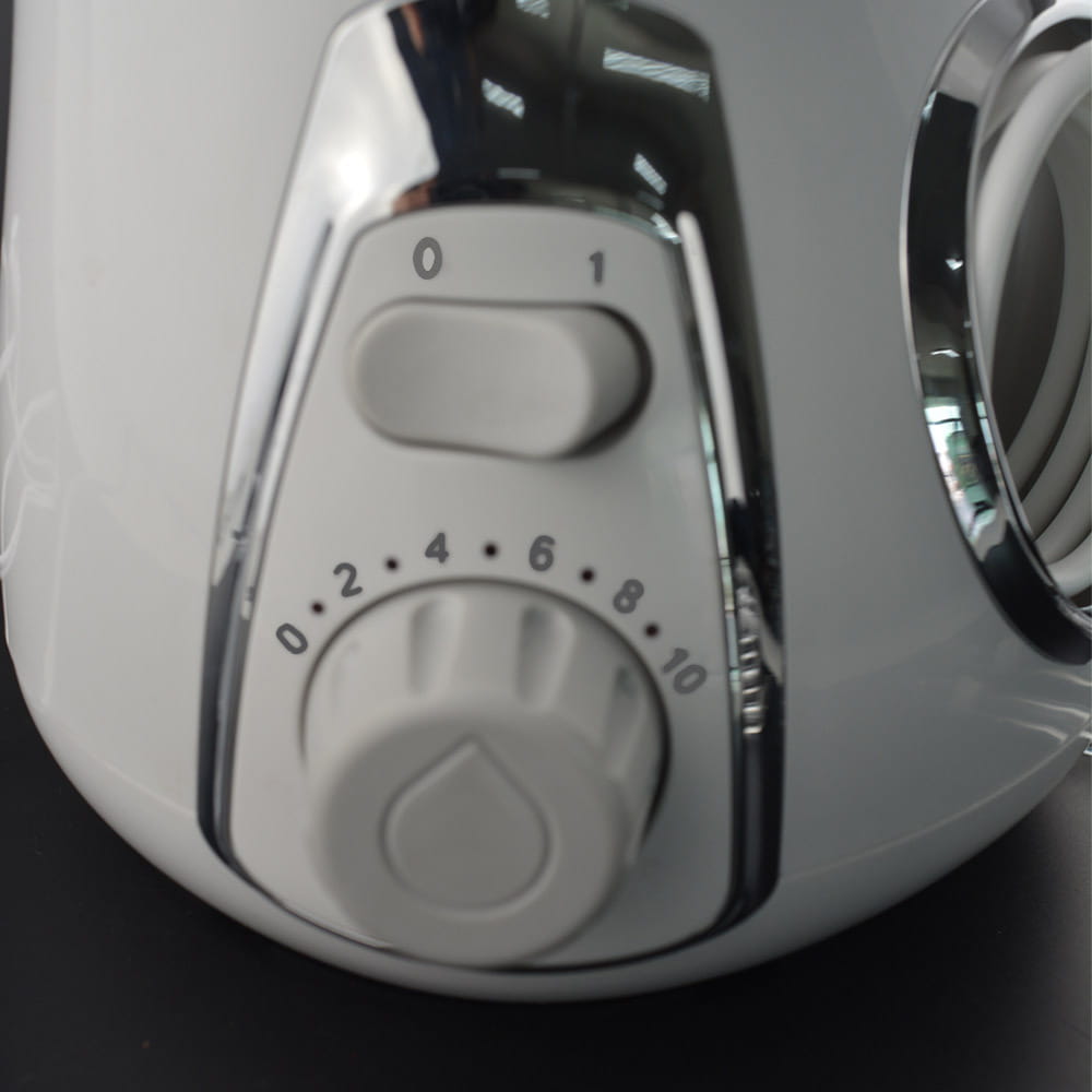 modern electric tooth punch electric tooth flosser in white with chrome accents and dual control dials for pressure and flow settings featuring a clear tank and brush head design.