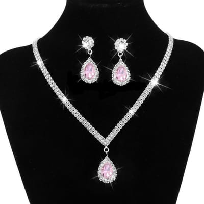 Silver v-shaped crystal bridal jewelry set featuring a sparkling silver necklace with a central teardrop-shaped pink gemstone and matching earrings for an elegant bridal jewelry ensemble.