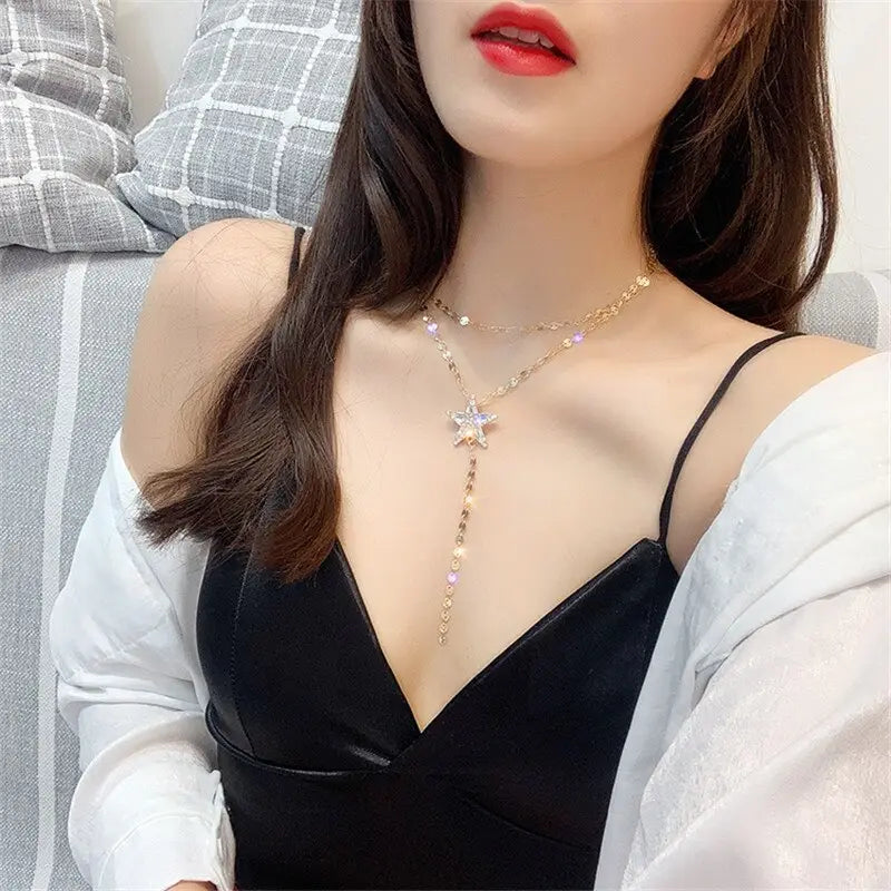 a gold-toned star crystal pendant necklace featuring sparkling rhinestones and a dangling chain worn as a layered choker highlighting the variable mso-font-signature and mso-font-pitch variable design elements