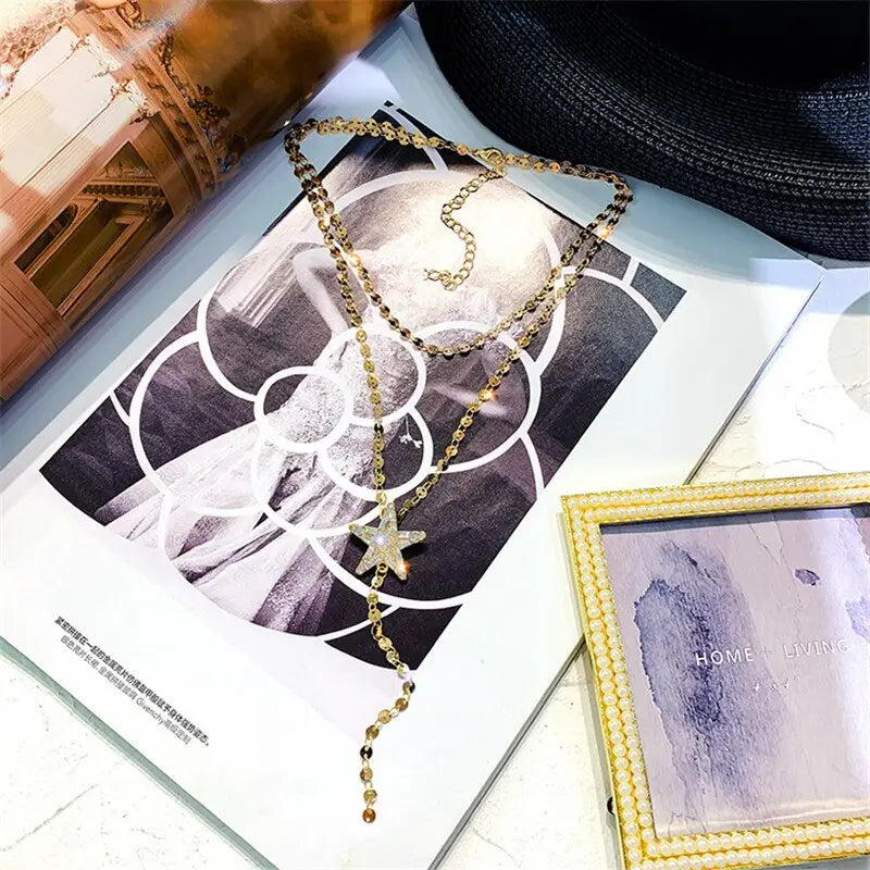 gold-toned layered necklace with a star-shaped crystal pendant and dangling beads designed with variable mso-font-signature and mso-font-pitch variable elements.
