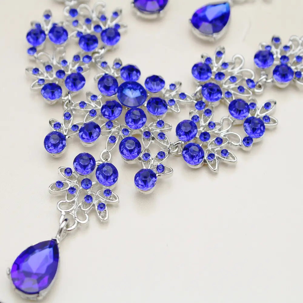 A sparkling royal blue crystal necklace with intricate silver toned floral designs and a dangling teardrop pendant from the butterfly big water drop earring set.