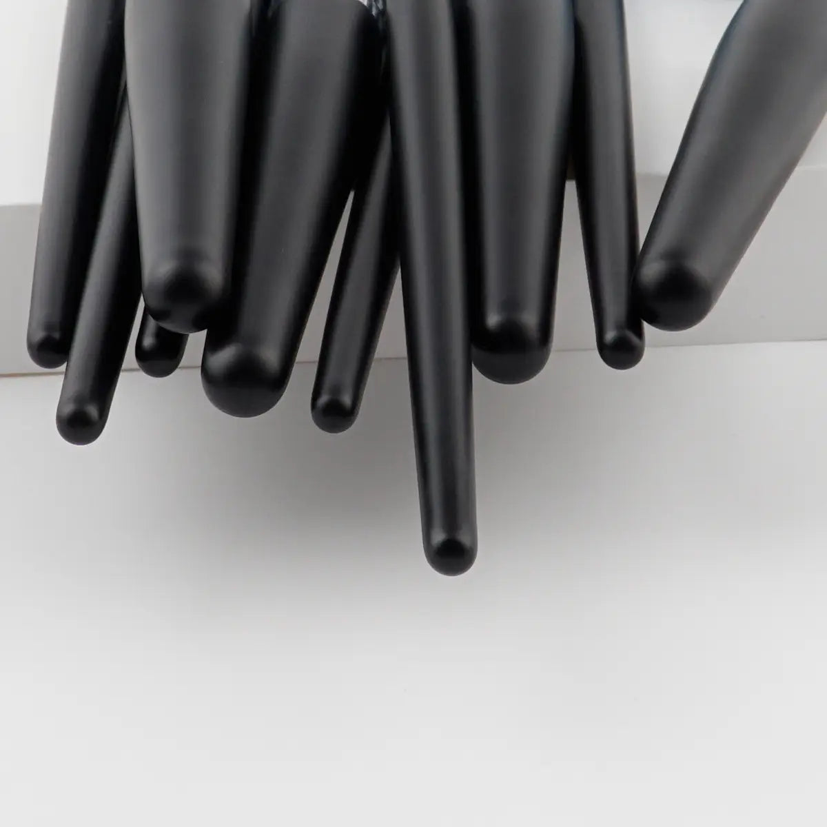 Set of sleek black makeup brushes with smooth tapered handles from a 10 piece purple gradient makeup brush set.