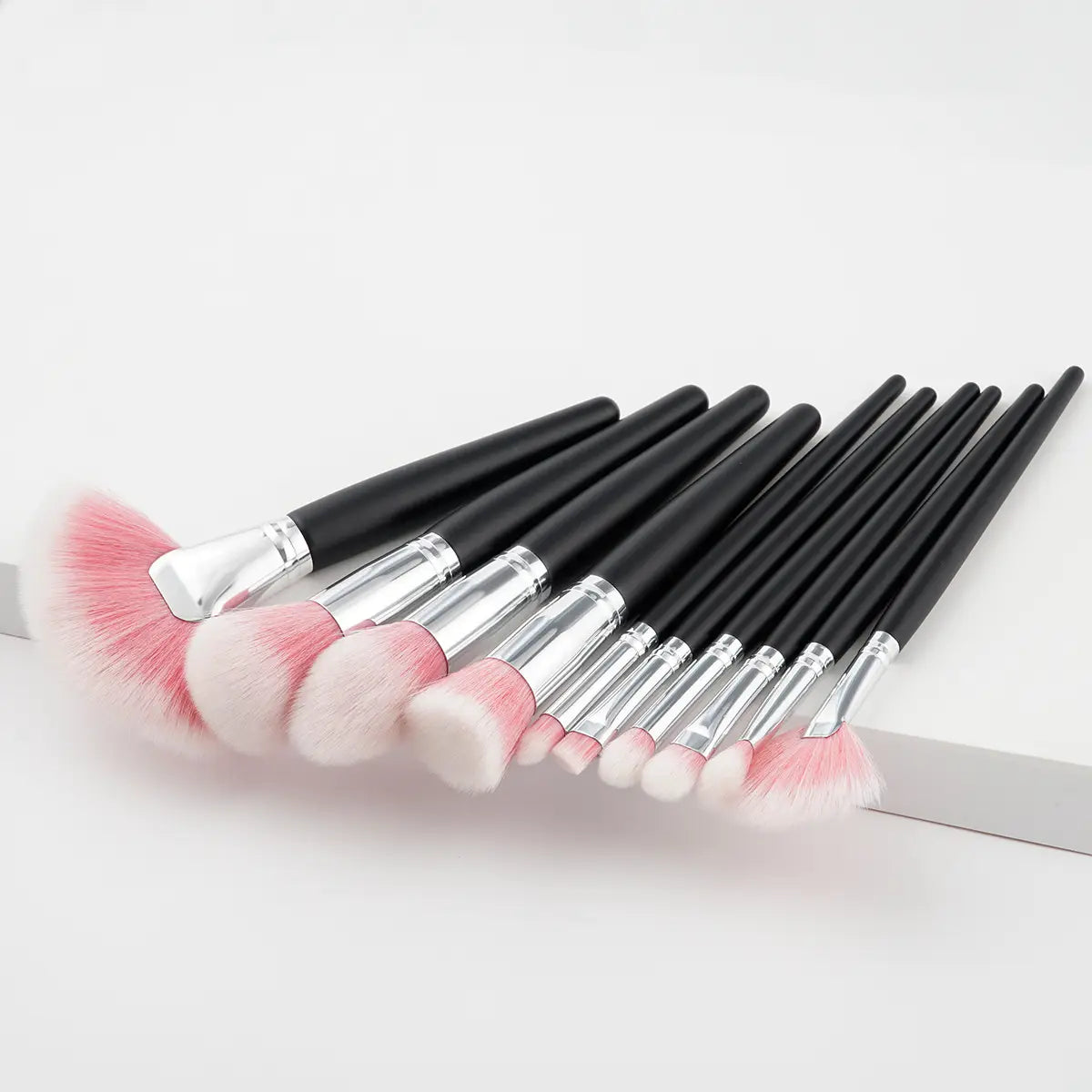 Set of ten black-handled makeup brushes with silver ferrules and soft pink-to-white synthetic bristles in a 10 piece purple gradient makeup brush set.