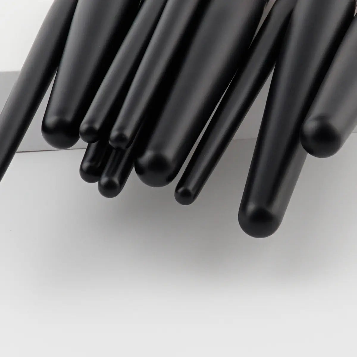 black cylindrical pen caps with smooth glossy finish featured in a 10 piece purple gradient makeup brush set for professional makeup brush storage and protection.