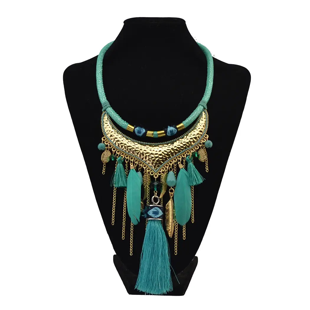 A vibrant turquoise and gold statement necklace featuring a textured metallic crescent centerpiece with feather leaf tassel charms and an eye motif pendant showcasing original jewelry feather design.