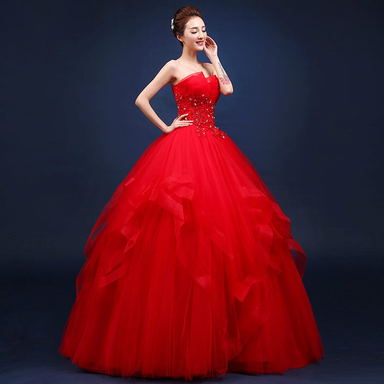 A vibrant red strapless ball gown wedding dress with a fitted bodice adorned in sparkling embellishments and a voluminous layered tulle skirt, showcasing a neatly slim silhouette.