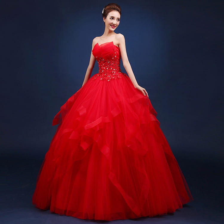 A vibrant red strapless ball gown wedding dress with a neatly slim fitted bodice adorned with sparkling embellishments and a voluminous tulle skirt.